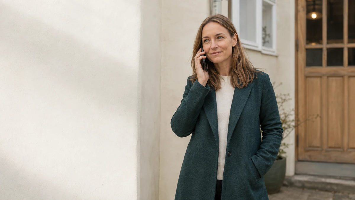 Virksomhedsejer i grøn frakke tager en telefonsamtale udenfor